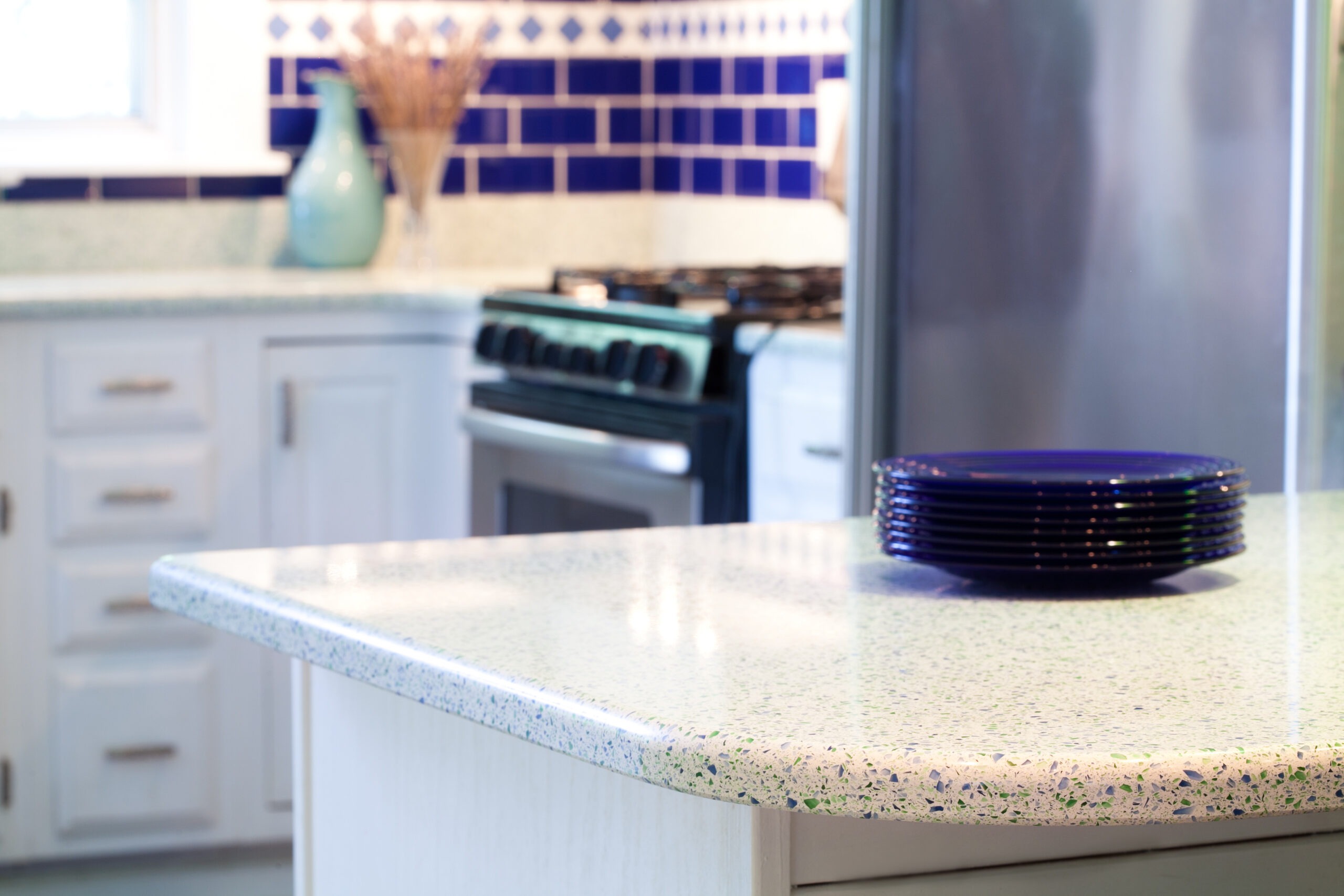 Kitchen countertop with light stone surface and blue tile backsplash